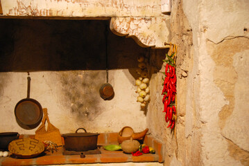 bundles of chili peppers and onions hanging on rough kitchen wall