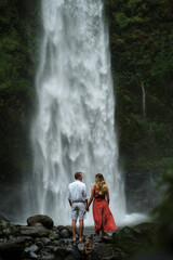 Beautiful young couple on a background of green rocks and a waterfall in Bali