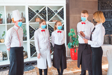 a team of waiters conduct a briefing on the summer terrace of the restaurant.