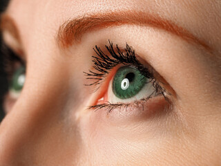 Female left blue eye tinted in green colour with special contact lens