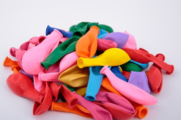 View of pile of multicolored balloons on white background.