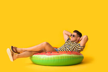 Young man with inflatable ring on color background