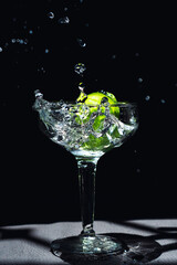 Bebida en copa de cristal con limones cayendo