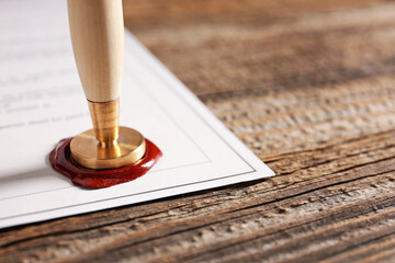 Document with notary public wax seal on table, closeup