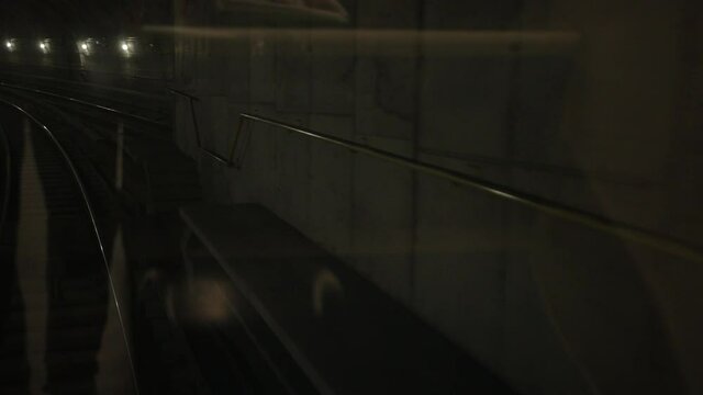 Dark underground train tunnel, deep down, subway car rides on rails in the subway, view of rails