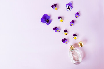 Composition, set with fresh beautiful colorful flowers, fragrant and spray bottle with women's perfume. Violets. Top view. Flat lay on purple background.