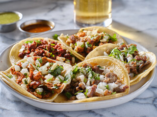 platter of mexican street tacos with carne asada, chorizo, and al pastor in corn tortillas