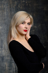 Fototapeta premium Young blonde plump woman with bright makeup in black bodysuit is posing at dark background, isolated with copy space. Concept of xxxl fashion and junk food