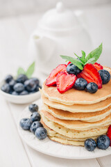 Classic american pancakes with fresh berry on white wood background. Summer homemade breakfast.