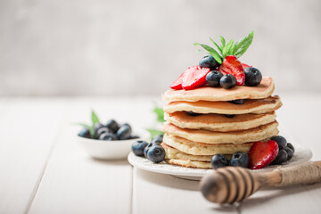 Classic american pancakes with fresh berry on white wood background. Summer homemade breakfast.