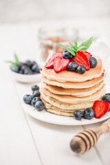 Classic american pancakes with fresh berry on white wood background. Summer homemade breakfast.