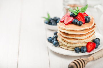 Classic american pancakes with fresh berry on white wood background. Summer homemade breakfast.