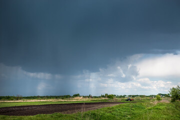 Thunderclouds over meadows and fields. The sun and jets of rain in the sky.