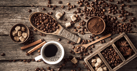 Coffee cup with coffee beans on wood background.