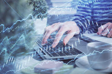 Double exposure of woman hands typing on computer and forex chart hologram drawing. Stock market...