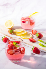 Cold pink strawberry flavoured jin and tonic garnished with fresh fruits and mint leaves.