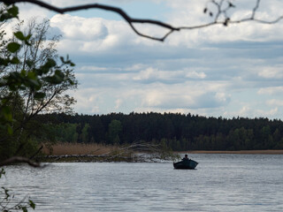 Wiele/Poland - 15.05.2020. Lake in Kaszuby surrounded by the trees. Fishing boat on the lake. Poland