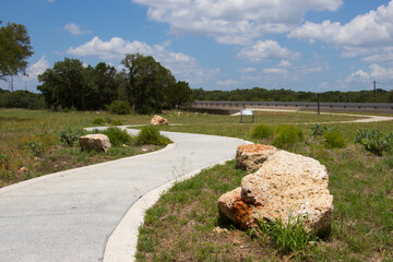 a curving concrete trail with large rocks on either side