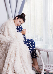 Young brunette in pajamas with a white mug in her hands
