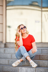 Beautiful girl walk in the summer Kiev City. Young woman tourist on a street. Street style portrait. Stylish girl near a river weared in red casual outfit. Life style. Local tourism. Srteet walk. 