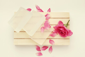 Soap bar and rose flower. Base for making soap and pink rose bud on wooden pallet. Top view.