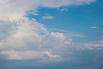 Blue sky background with white dramatic clouds and sunlight, vast sky background