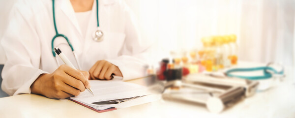 Close-up hands Female doctor in a white coat and headphones on duty, recording clipboard, taking medication on the hospital desk 