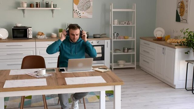 Handsome young man listening to music while working at home