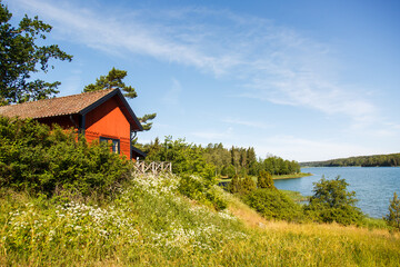 Fototapeta na wymiar Red summer garden cottage in Sweeden. Traditional Sweden wooden old house. Life on the one of Sweeden islands