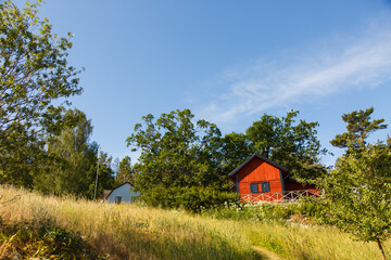 Fototapeta premium Red summer garden cottage in Sweeden. Traditional Sweden wooden old house. Life on the one of Sweeden islands