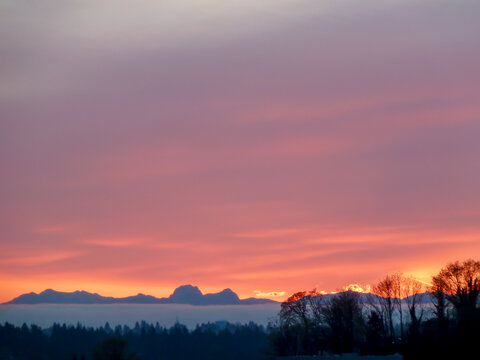 Sunrise over Cascade Mountain Range in Washington State with violet, orange, and yellow sky.