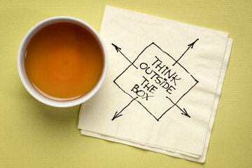 think outside the box inspirational reminder or advice - black pen drawing on a cocktail napkin with a cu of coffee, business, education and personal development concept