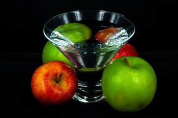 art photo glass of water red and green apples on a black background
