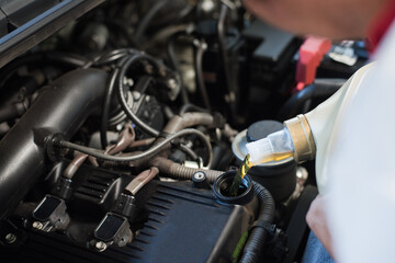 Fototapeta na wymiar Car mechanic fills a fresh lubricant engine oil