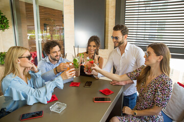 Group of colleagues drinking cocktails after work in cafe bar