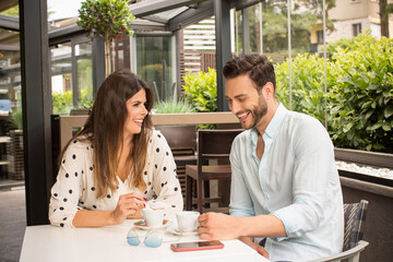 Attractive young couple drinking coffee in garden restaurant