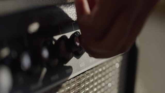 Young Black Hand Adjusts Bass Knob on Amp, Close Up, Slow Motion