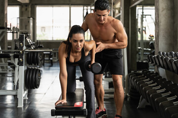 Fototapeta premium woman workout with dumbbell with trainer in gym and fitness club