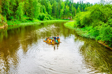 People on an inflatable raft float on the river among the mountains and forests in summer.