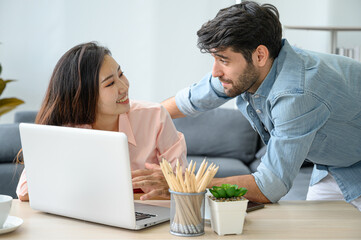 Happy and relax  lifestyle of young couple lover wearing casual dress together working on laptop notebook computer in living room at home.