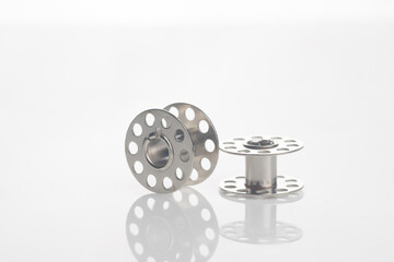 Set of metal bobbins isolated over white reflective background