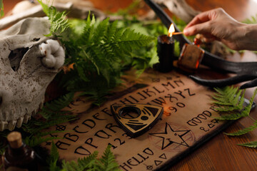Mystic ritual with Ouija and candles. Devil's board concept, black magic or fortune telling rite...