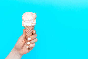 A woman's holds an ice cream cone on blue background, view from the front, 19th World Ice Cream Day