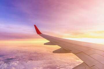 Obraz premium Aircraft left wing on the sky above the clouds at Sunrise dawn.