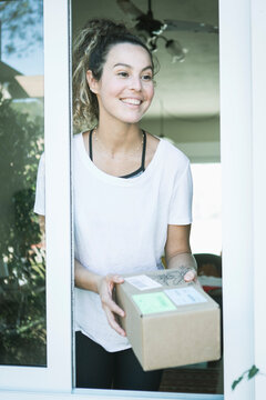 Beautiful caucasian young woman smiling receiving mail delivery package at home during covid 19 pandemic. 