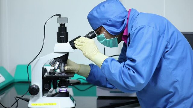 Indian Scientists checks microorganisms of corona virus with microscope. Experiment using microscope for testing in laboratory.