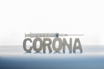 The word corona virus,and a syringe,isolated over blue background