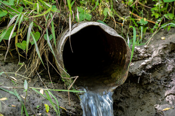 Water flowing from the open outlet of a metal agriculture drainage tile