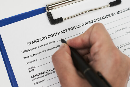 Signing standart contract for live performance by musicians. A musician filling live performance contract