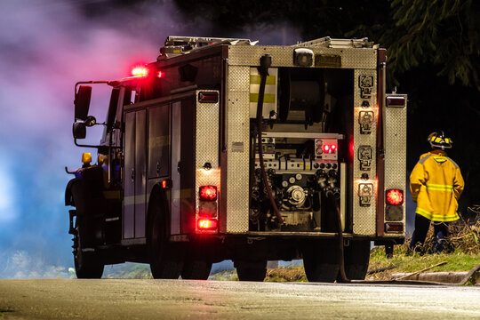 Fire brigade on scene in residential community in response to reports of fire on open lot. Fireman in uniform fireproof coat/ jacket & helmet.